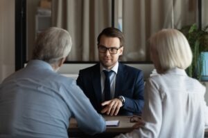 An investment fraud lawyer serving clients in Seattle, sitting with his elderly clients, discussing their legal options.