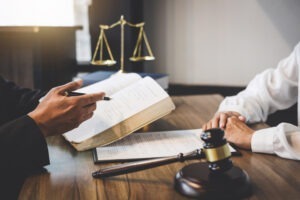 Lawyer sits at desk with client and explains how to report a pump and dump scheme.