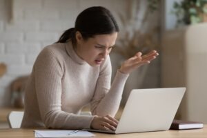 An unhappy woman looks at her computer and wonders if Crypto.com can recover stolen crypto.