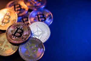 Several cryptocurrency coins, with someone nearby wondering if Bitstamp can recover their stolen crypto